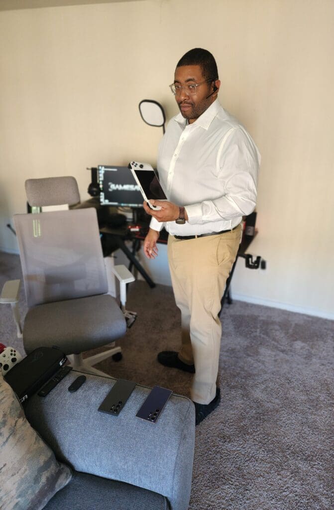 A man standing in front of a chair holding an ipad.